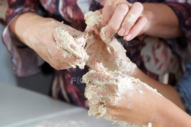 Imagem cortada de mãos de mãe e filho na massa de farinha — Fotografia de Stock