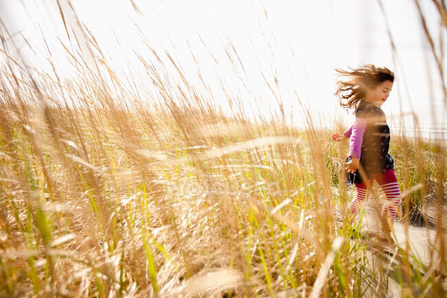 Menina correndo através de grama longa — Fotografia de Stock