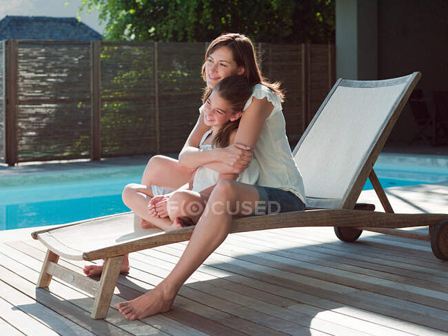 Ragazza e madre sulla poltrona a bordo piscina — Foto stock