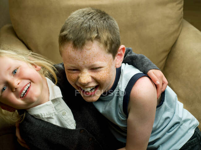 Um irmão e uma irmã numa cadeira de braço — Fotografia de Stock