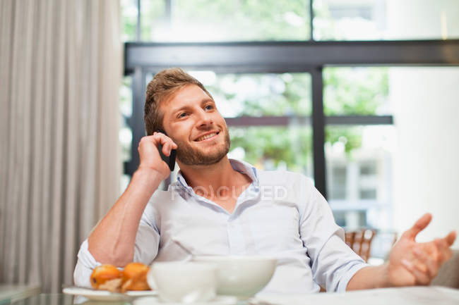 Мужчина разговаривает по телефону за завтраком — стоковое фото