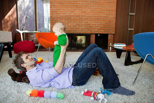 Father playing with baby son in living room — Stock Photo