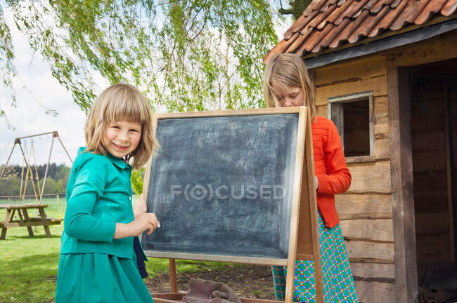 Zwei Mädchen draußen mit Tafel — Stockfoto