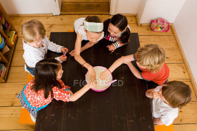 Niños compartiendo comida en la cocina - foto de stock