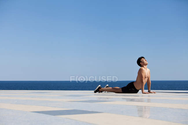 Atleta praticando ioga na superfície de azulejos — Fotografia de Stock