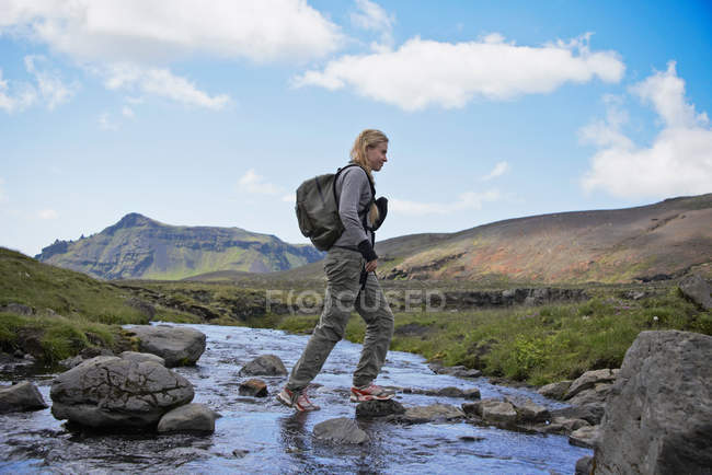 Caminhante cruzando córrego rural rochoso — Fotografia de Stock