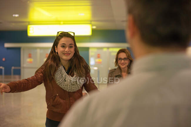 Дівчина-підліток прибуває в аеропорт, чоловік на передньому плані — стокове фото