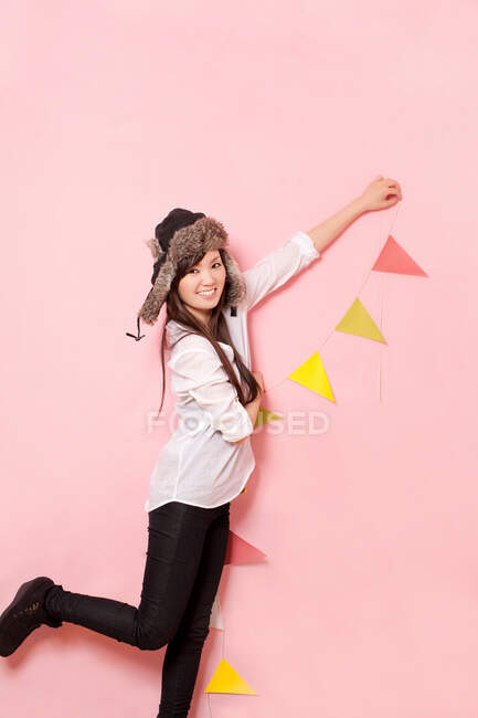 Mid adult woman holding bunting against pink background — Stock Photo