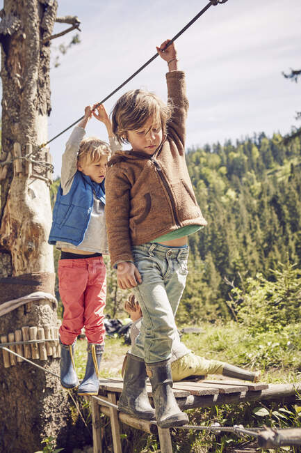 Deux enfants traversent un pont à corde unique — Photo de stock