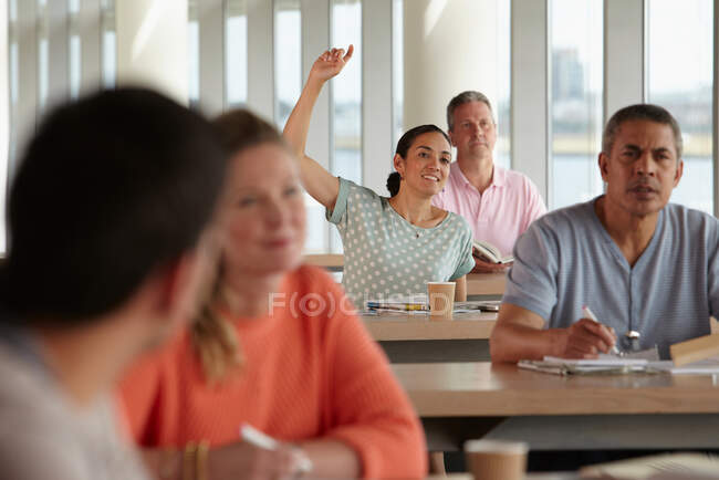 Estudantes maduros em sala de aula, mulher com a mão para cima — Fotografia de Stock