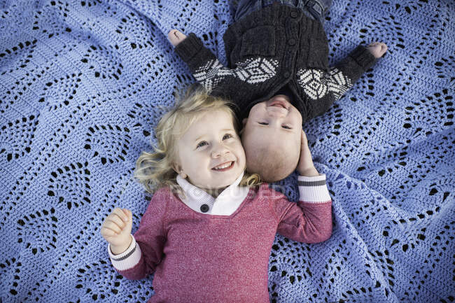 Retrato de arriba de la niña en manta de picnic azul con el hermano bebé - foto de stock