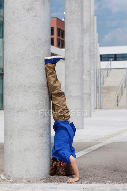 Boy doing headstand by column — Stock Photo