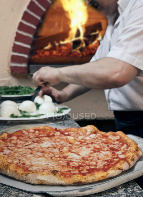 Man making pizza on spatula in kitchen — Stock Photo