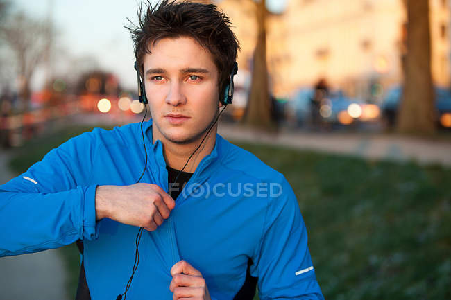 Runner escuchando auriculares al aire libre - foto de stock
