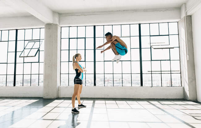 Вид сбоку на мужчину в спортзале, прыгающего в воздухе, согнутые колени — стоковое фото