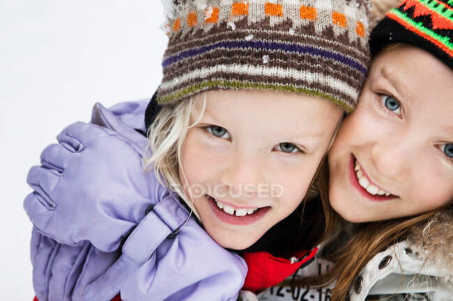 Smiling girls hugging in snow — Stock Photo