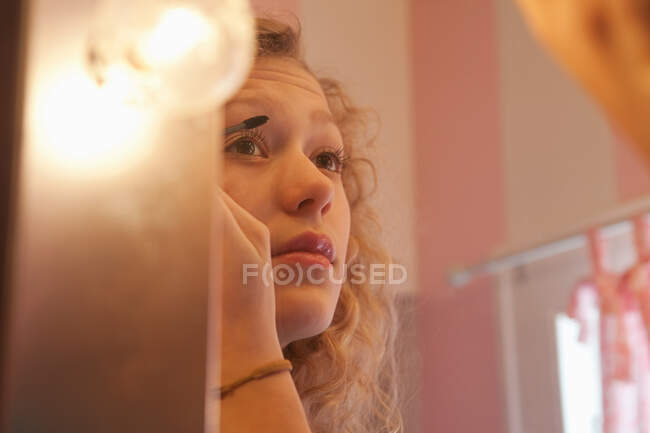 Teenage girl applying mascara in mirror — Stock Photo