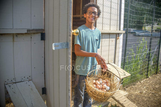 Portrait de garçon dans le poulailler avec panier d'œufs — Photo de stock