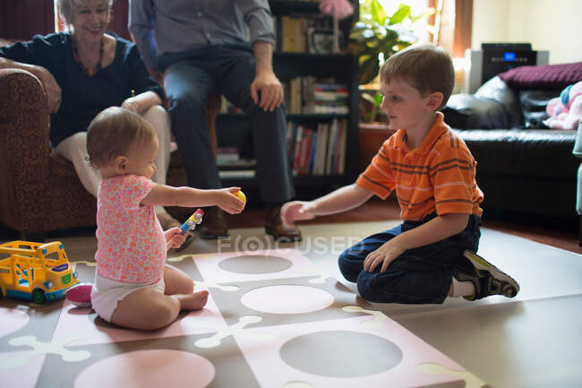 Brother playing with little sister on floor — Stock Photo
