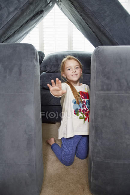 Girl stopping entry into tower of cushions in living room — Stock Photo