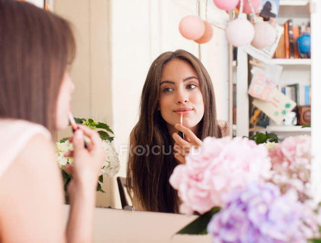 Woman applying make up in mirror — Stock Photo