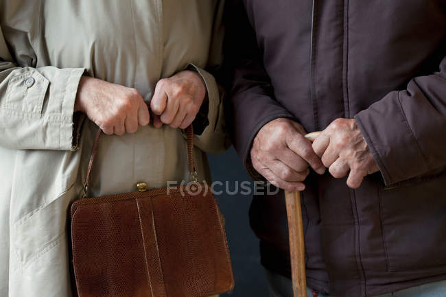 Hombre mayor con bastón, mujer mayor con bolso - foto de stock