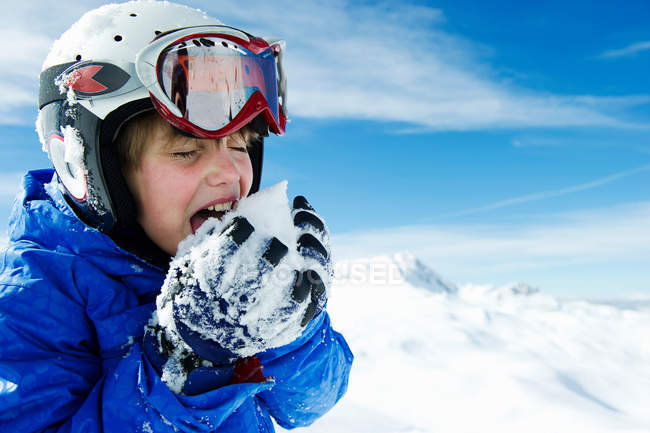 Boy tasting snowball on mountain — Stock Photo