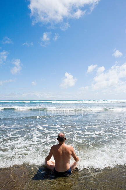 Окленд, мужчина медитирует на пляже Муривай — стоковое фото