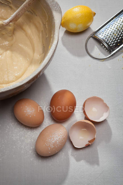 Cáscaras de huevo, harina, limón y masa en la mesa - foto de stock