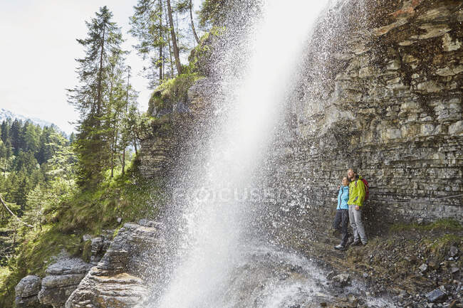 Молода пара, що стоїть під водоспадом, пильнує, Тіроль, Австрія. — стокове фото