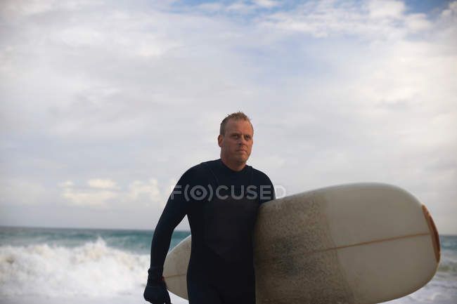 Surfista che trasporta bordo sulla spiaggia — Foto stock