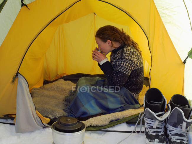 Female skier having a drink in a tent — Stock Photo