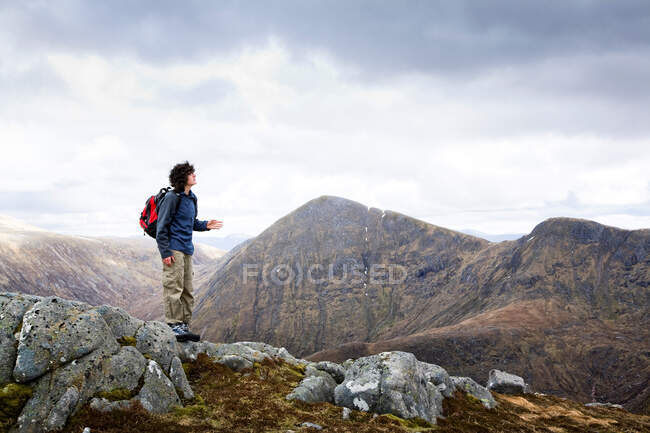 Junger Mann steht auf einem Felsen und blickt in den Himmel — Stockfoto