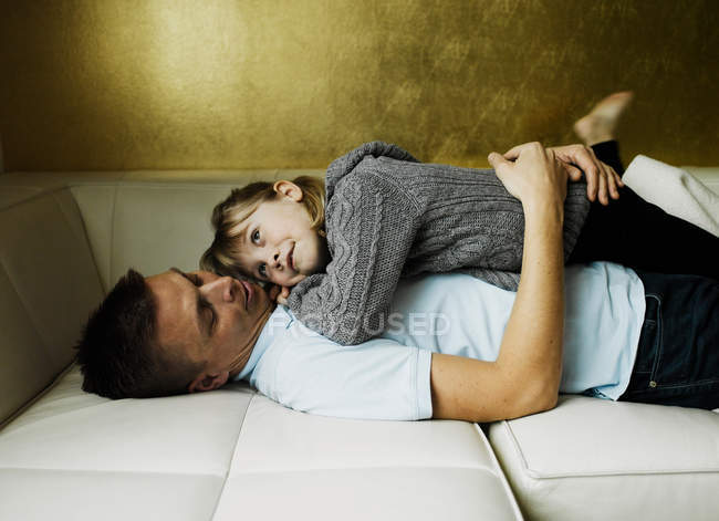 Отец и дочь отдыхают на диване — стоковое фото