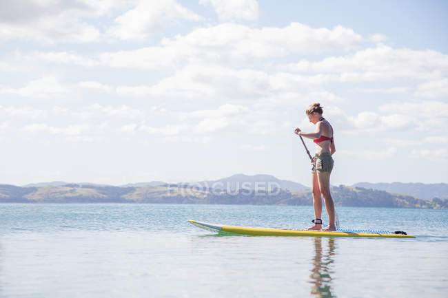 Femme adulte moyenne debout paddleboard en mer — Photo de stock
