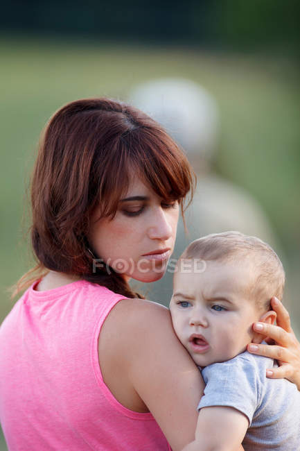 Mother holding crying baby outdoors — Stock Photo