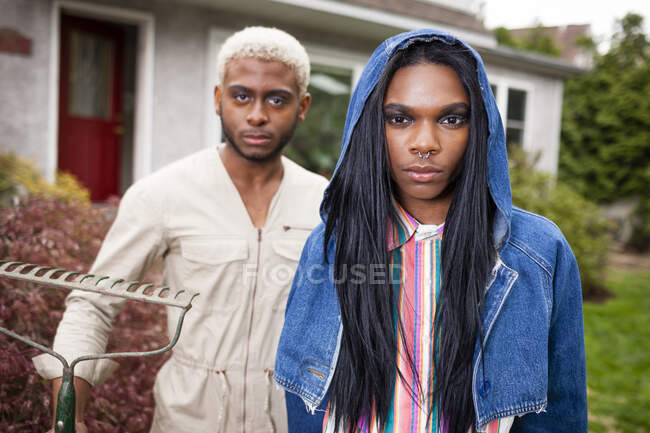 Due giovani uomini in posa nel cortile anteriore con rastrello — Foto stock