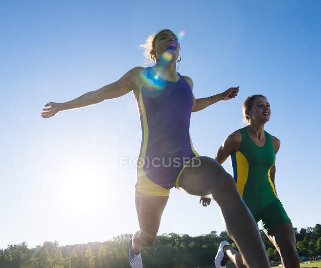 Dos atletas femeninas en pista de atletismo, al final de la carrera - foto de stock