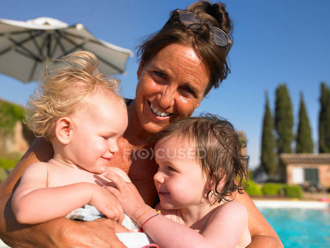 Mère tenant des filles près de la piscine — Photo de stock