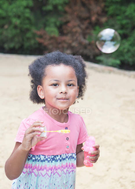 Chica soplando burbujas al aire libre - foto de stock