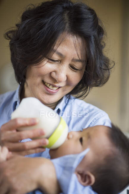 Grandmother feeding milk to grandson — Stock Photo