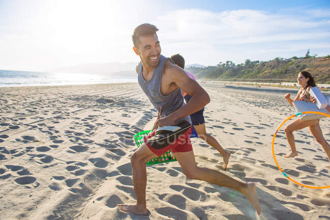 Group of friends running on beach, laughing — Stock Photo