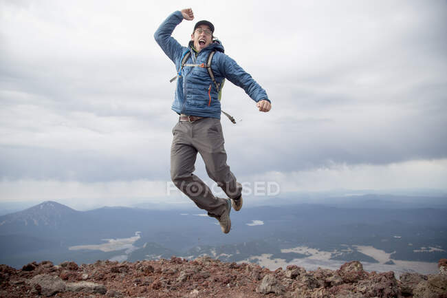 Junger Mann springt vor Freude auf den Gipfel des Südschwestervulkans, Bend, Oregon, USA — Stockfoto