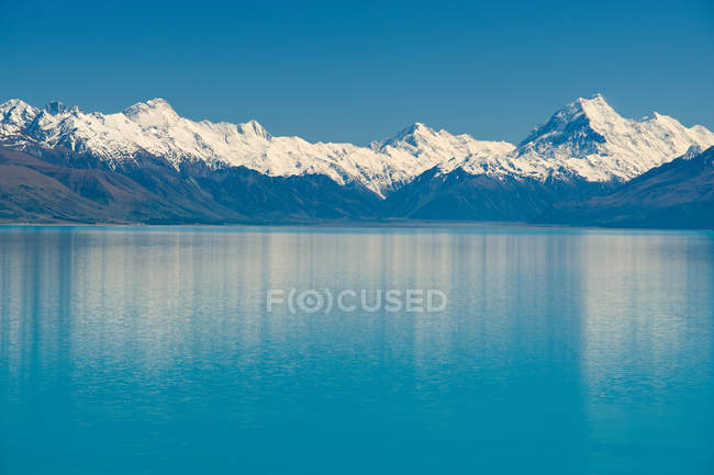 Snowy mountains and rural lake — Stock Photo
