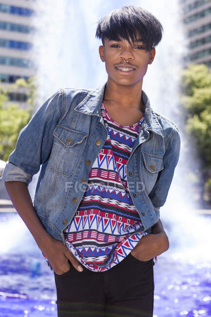 Portrait of young man in front of city fountain — Stock Photo