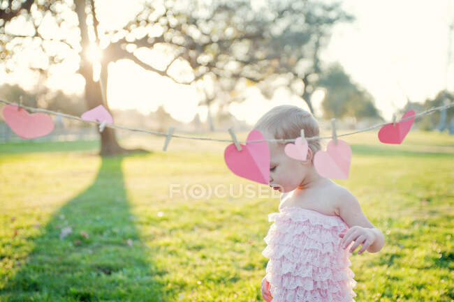 Young girl next to heart shapes on washing line — Stock Photo