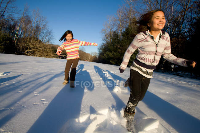 Две девушки бегут по снегу — стоковое фото