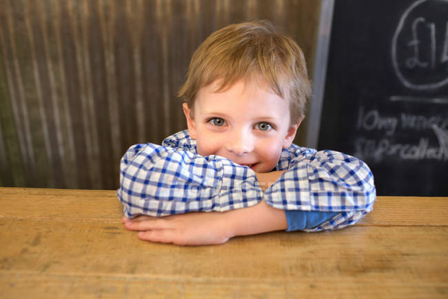 Улыбающийся мальчик, опирающийся на прилавок — стоковое фото