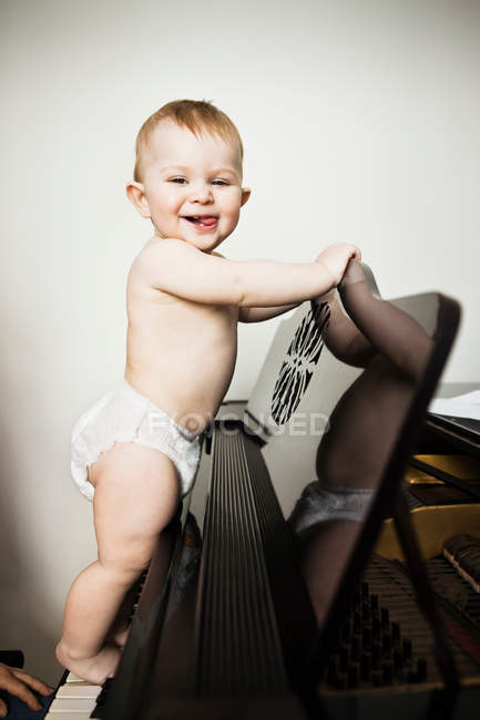 Bébé fille escalade sur piano — Photo de stock