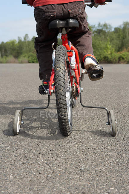 Обрізане зображення дитини на велосипеді зі стабілізаторами — стокове фото